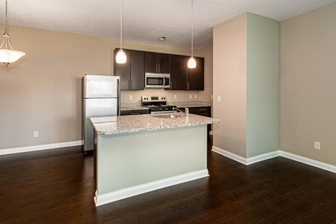 A kitchen with a refrigerator, microwave, and stove top oven.