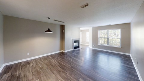 A spacious room with wooden flooring and a television set.