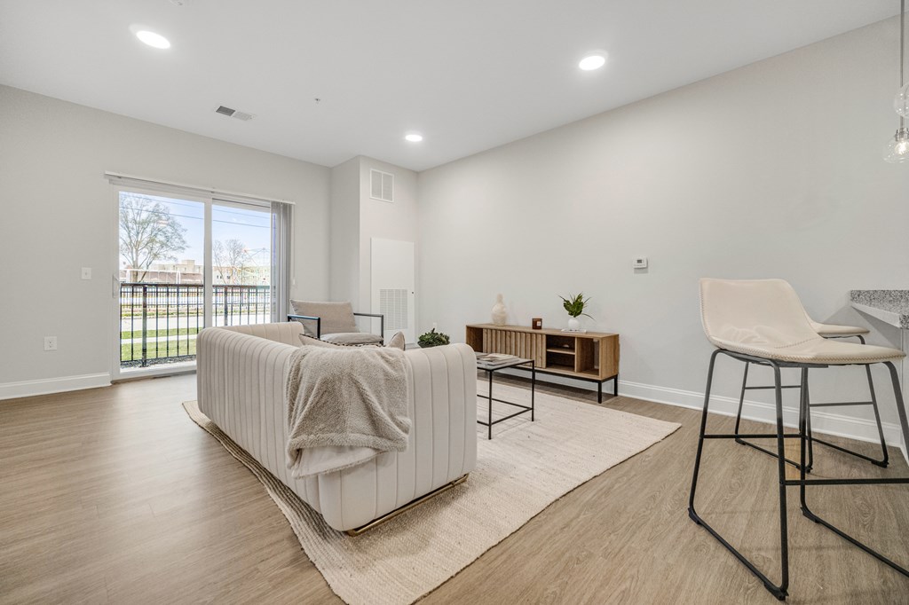 A white sofa with a grey blanket is in the middle of a room with a wooden floor and a white wall. at Park Lamont Townhomes Apartments, Cleveland 44106