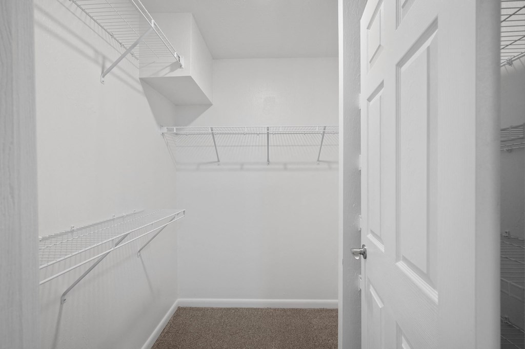 a walk in closet with white walls and a white door
