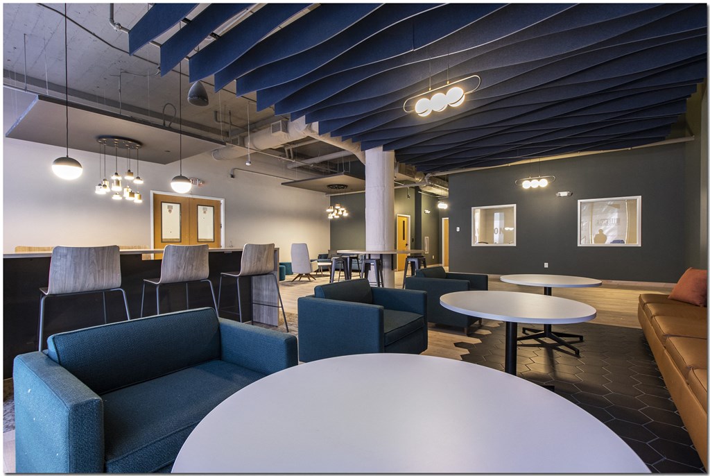 a large room with blue couches and chairs and tables and chairs
