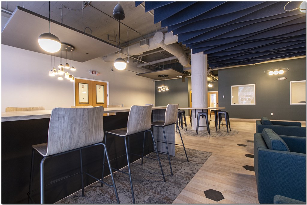 a bar with stools and tables in a room with couches and chairs