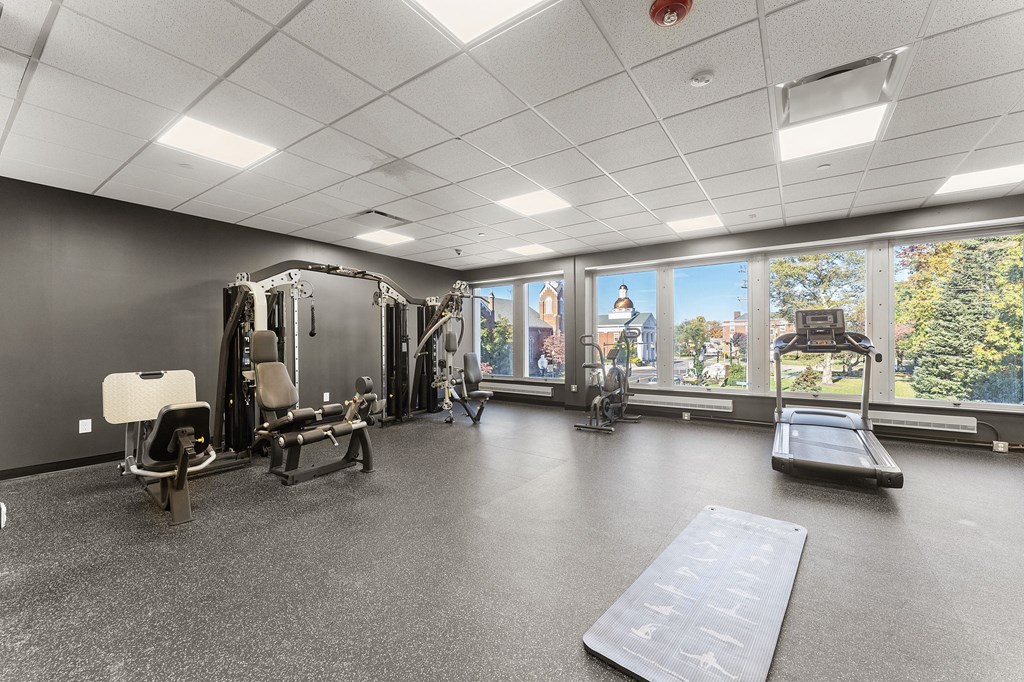 A spacious gym with a variety of equipment and a view of trees outside the window.