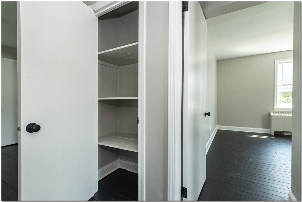 a room with white walls and a black floor and a white door with a black knob