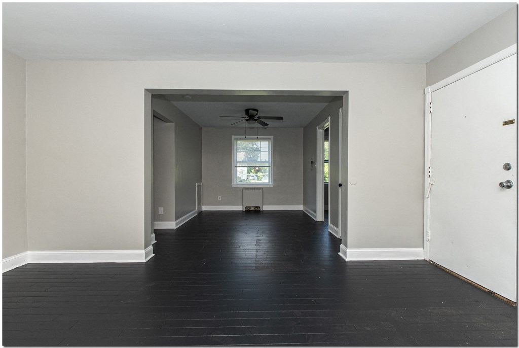 an empty room with a door open and a ceiling fan