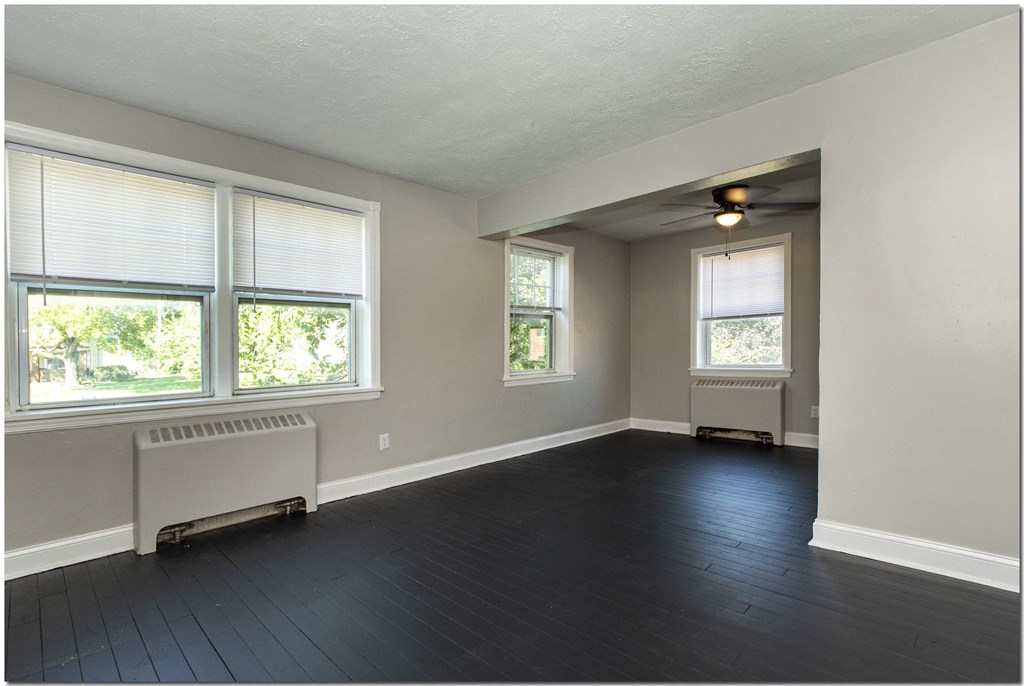 an empty room with a radiator and three windows