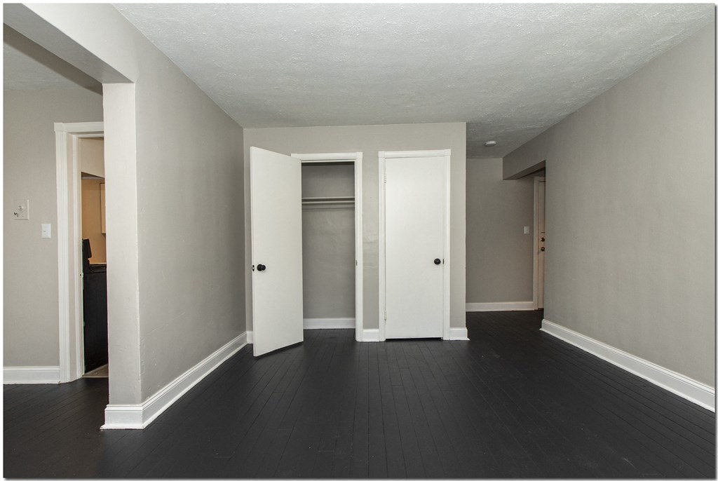a bedroom in an empty house with a dark wood floor and grey walls
