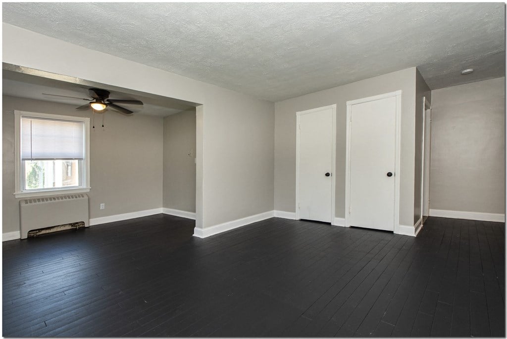 an empty living room with a ceiling fan and a window