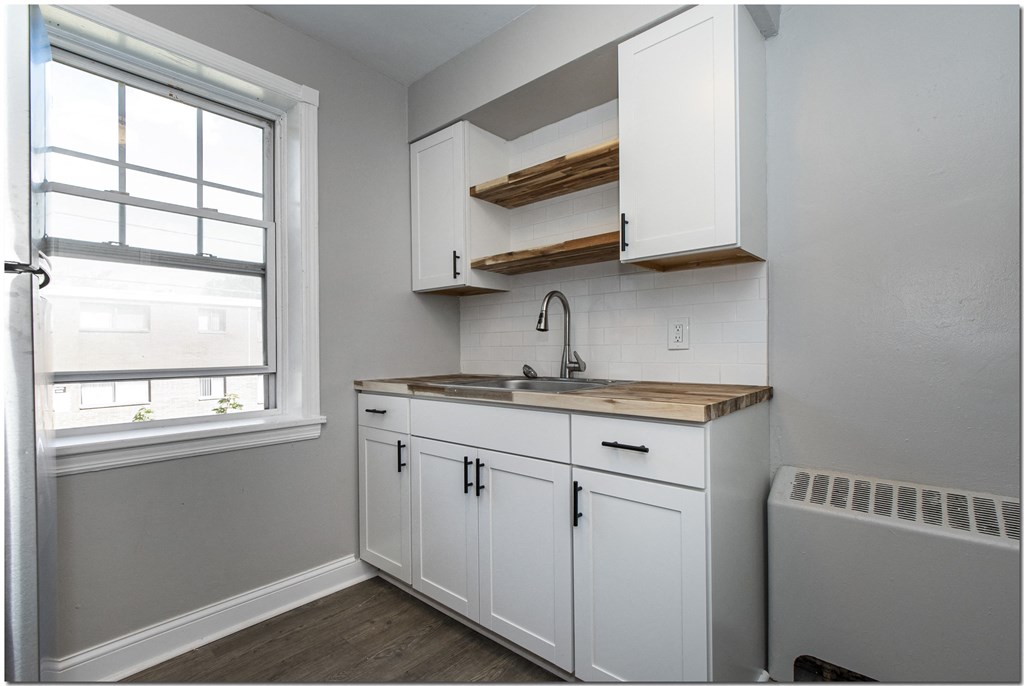 a small kitchen with white cabinets and a window