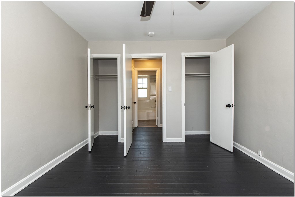 a bedroom with two closets and a bathroom in the background