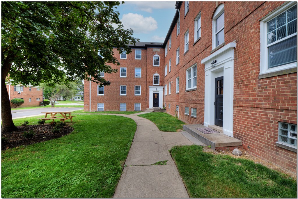 a walkway leading to a brick building with a picnic table in front of it