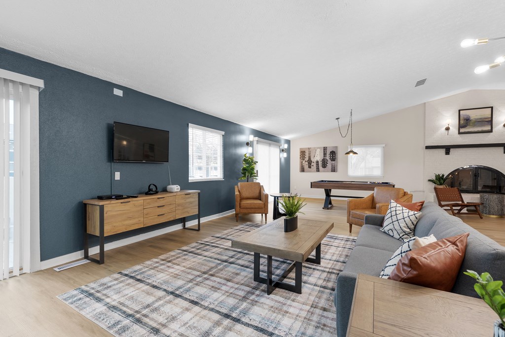 A living room with a grey couch, a wooden coffee table, and a flat screen TV mounted on the wall.
