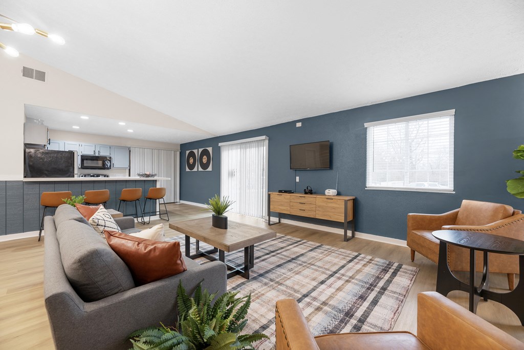 A living room with a grey couch, a wooden coffee table, and a flat screen TV mounted on the wall.