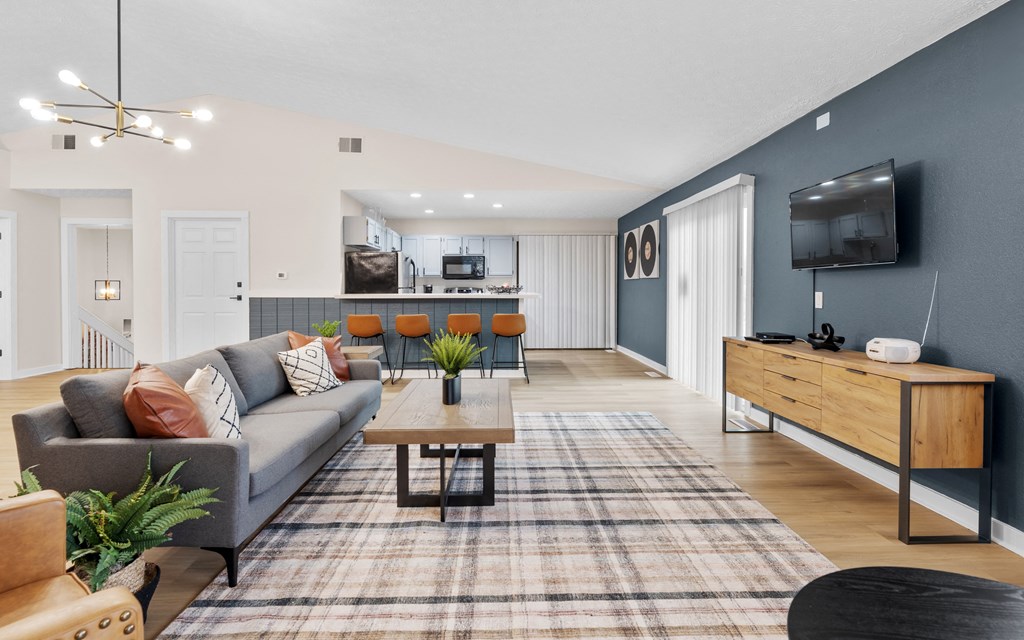 A living room with a grey couch, a coffee table, and a flat screen TV mounted on the wall.