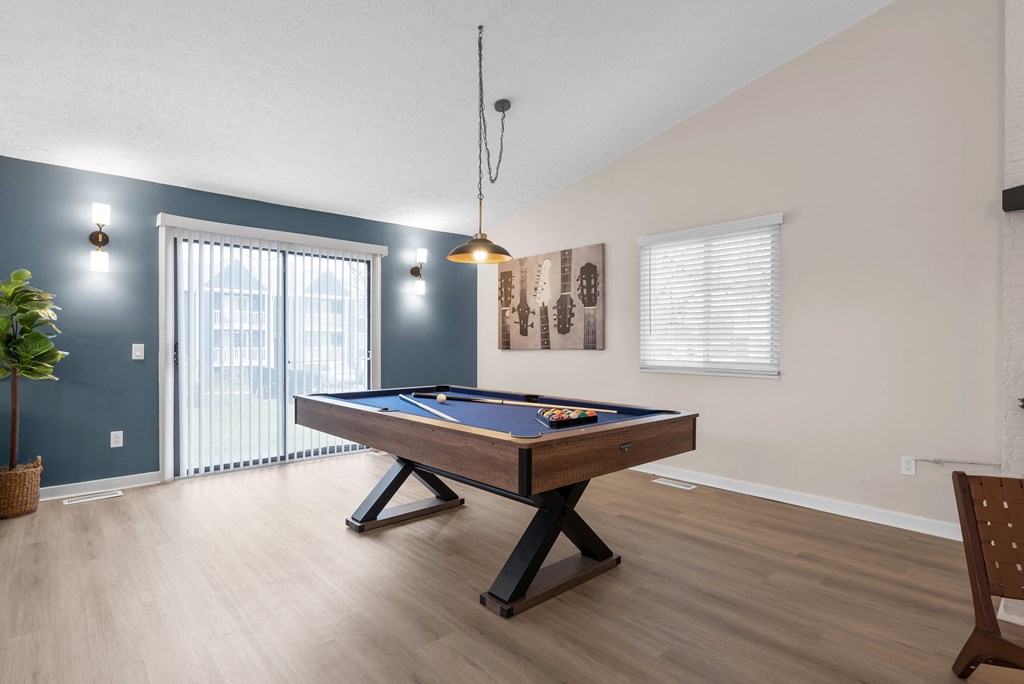 A pool table in a room with a chair and a plant.