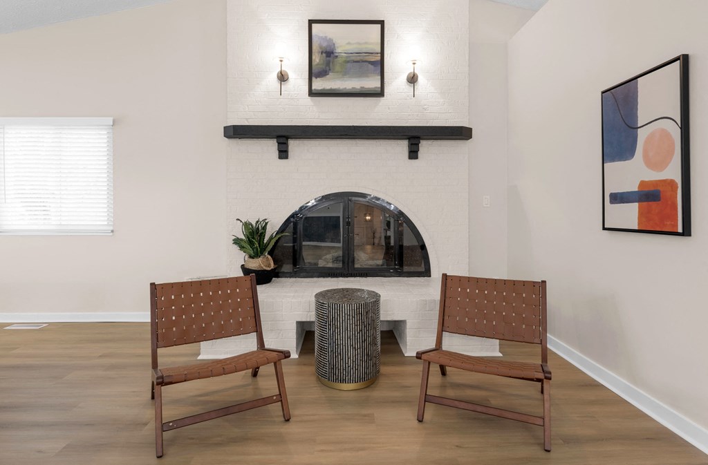 A living room with a fireplace and two chairs.