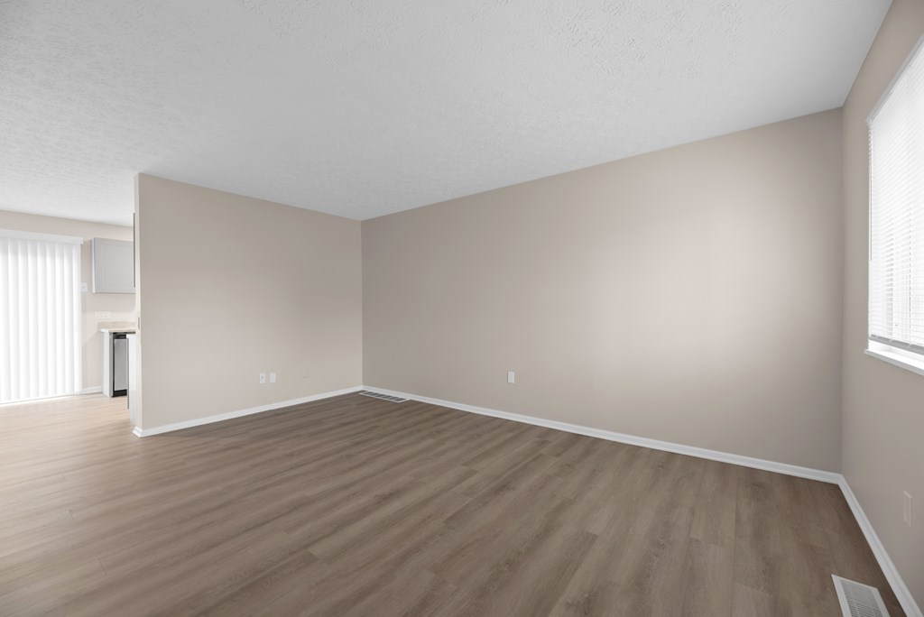 Empty room with wooden flooring and white walls.