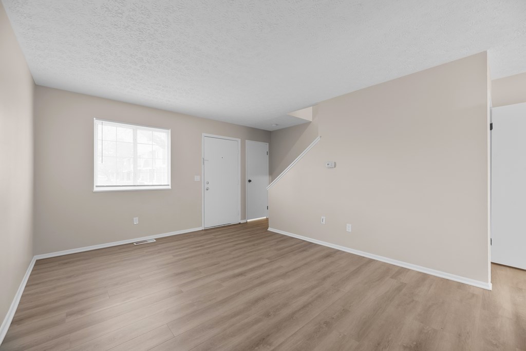 Empty room with wooden flooring and white walls.