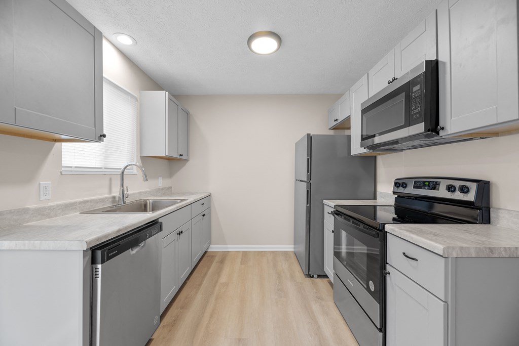 A kitchen with a sink, stove, and refrigerator.