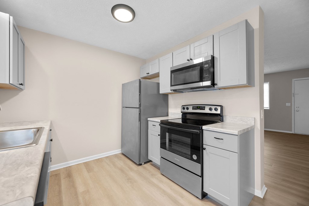 A kitchen with a stove top oven, microwave, and refrigerator.
