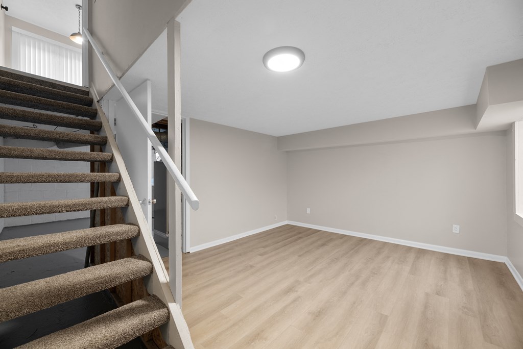 A room with a staircase and wooden flooring.