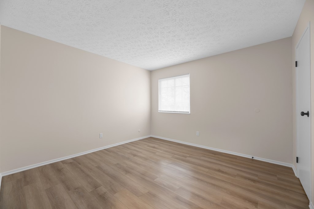 A room with wooden flooring and a window letting in light.