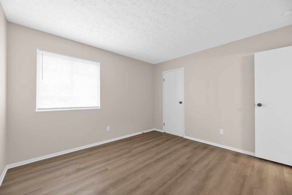 A room with a window and wooden flooring.