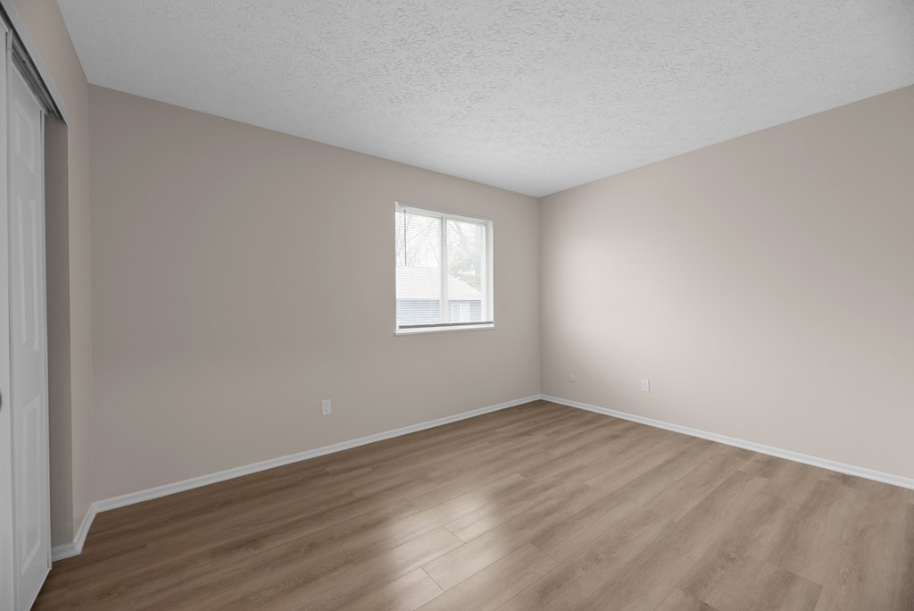 A room with a window and wooden flooring.