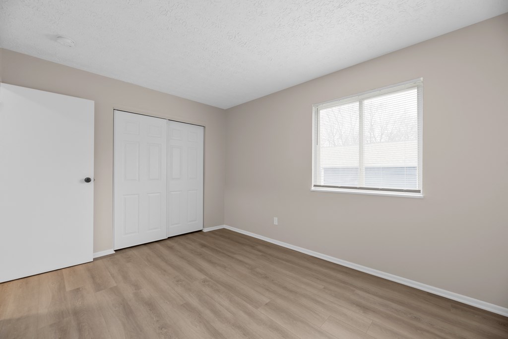 A room with a white door and a window with white blinds.