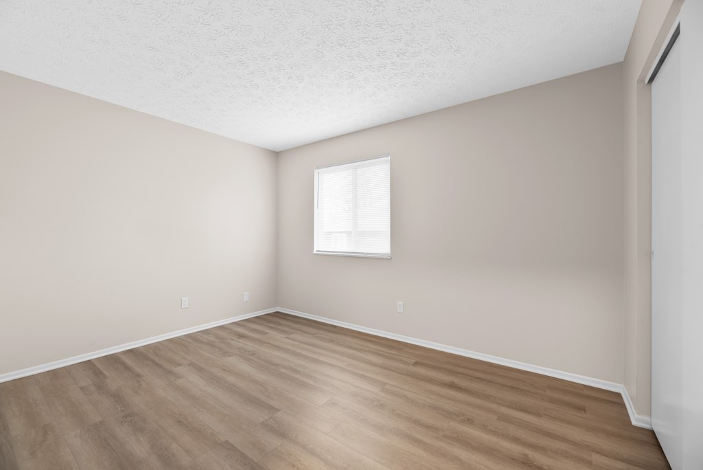 A room with a window and wooden flooring.