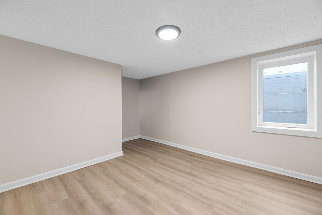 A room with a window and wooden flooring.