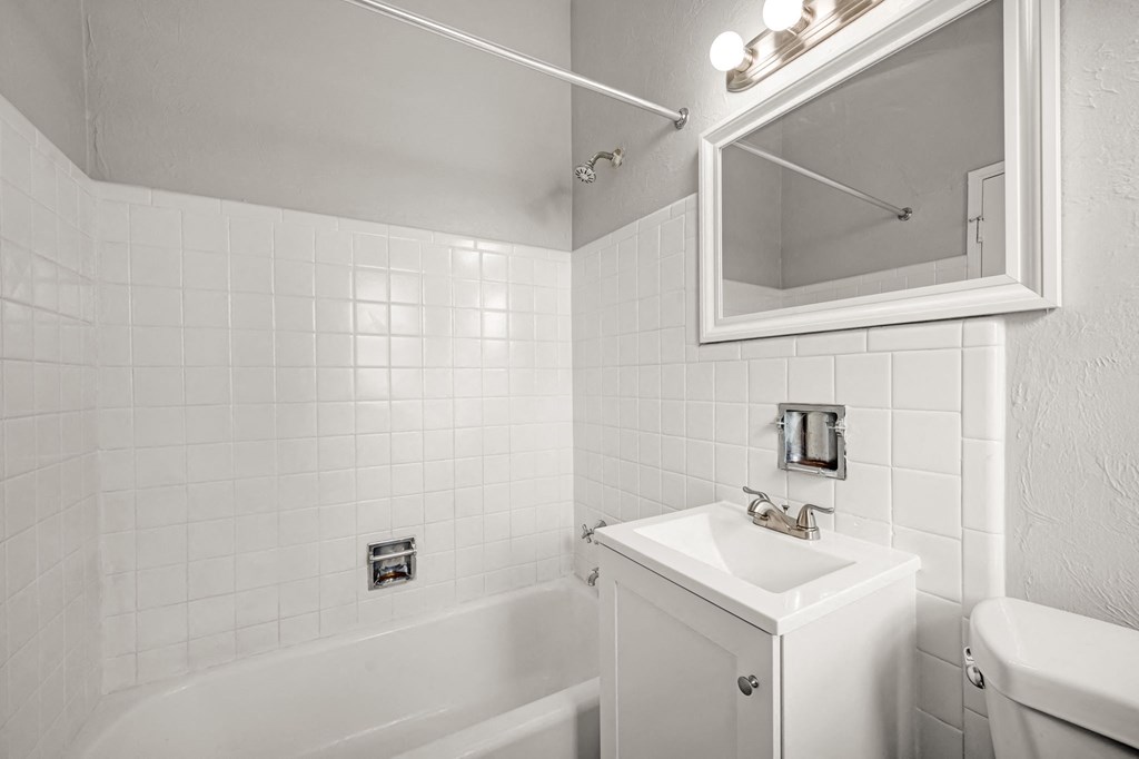 a white bathroom with a sink and a bath tub