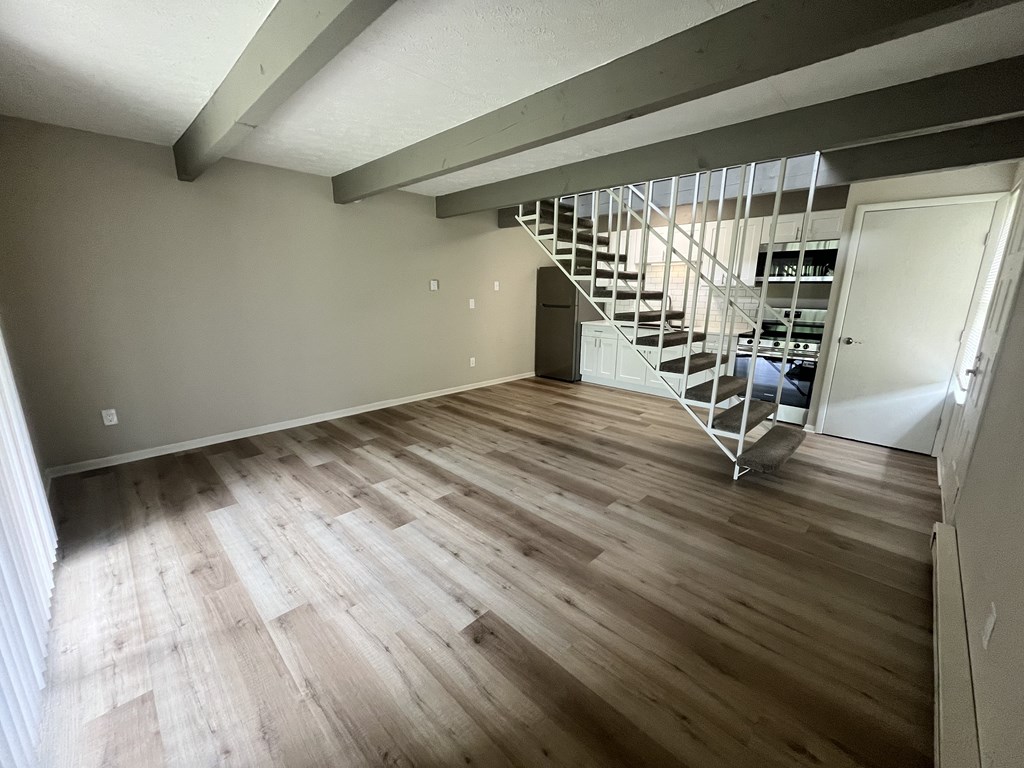 A room with wooden flooring and a staircase.