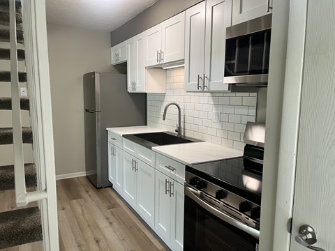 A kitchen with white cabinets and a black stove top oven.