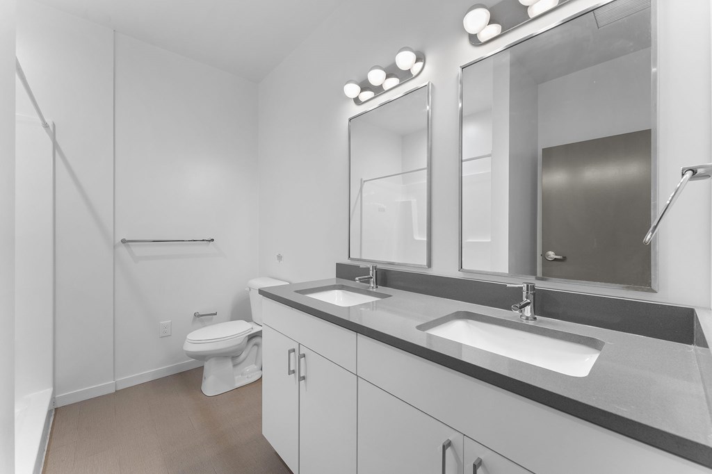 A bathroom with a toilet, sink, and mirror.