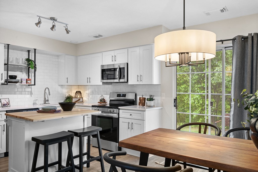 a kitchen with white cabinets and black appliances and a wooden table