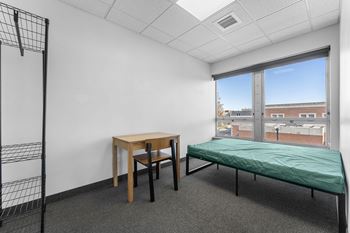 A room with a bed, table and chair.