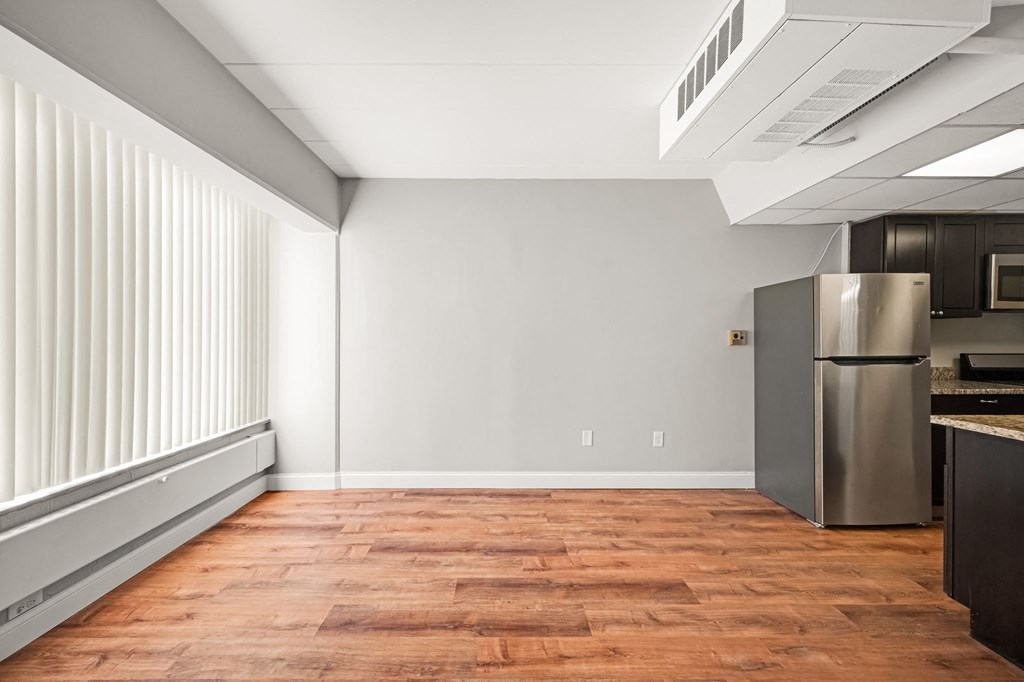 an empty kitchen with a stainless steel refrigerator and a window