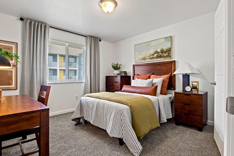A bedroom with a bed, nightstand, and chair. at Vivo Toledo Apartments, Toledo, Ohio