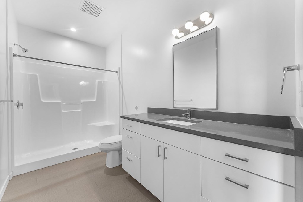 A white bathroom with a sink, mirror, and shower.