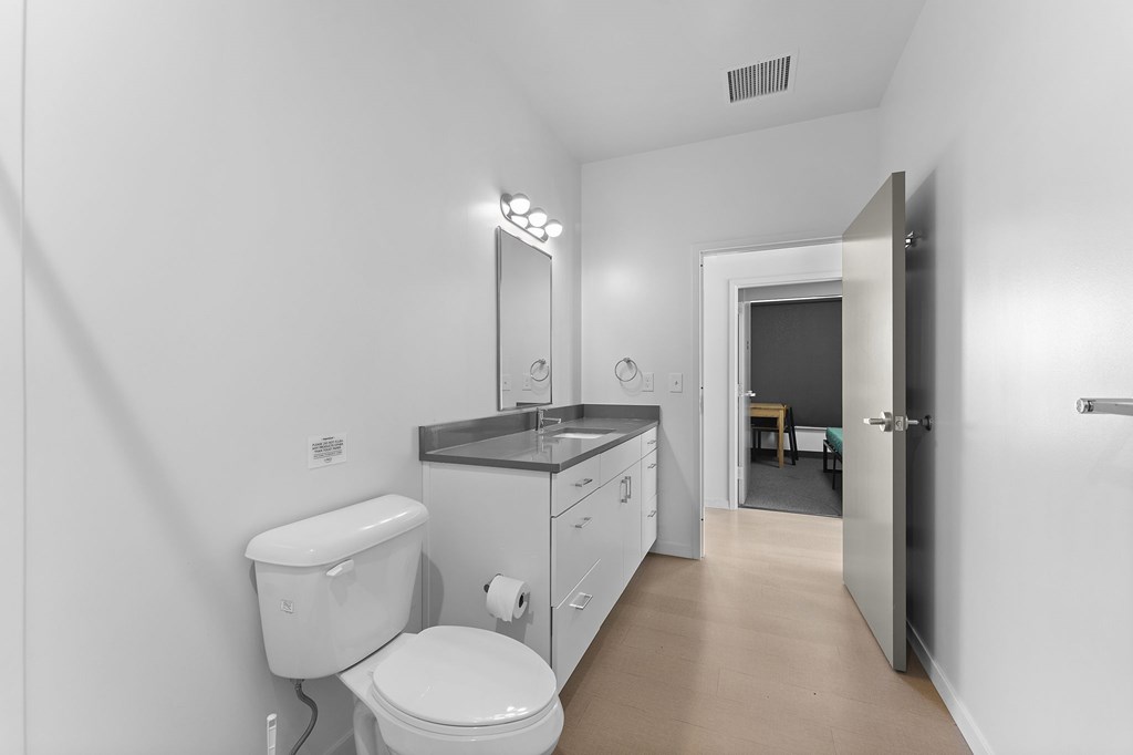 A white bathroom with a toilet, sink, and mirror.
