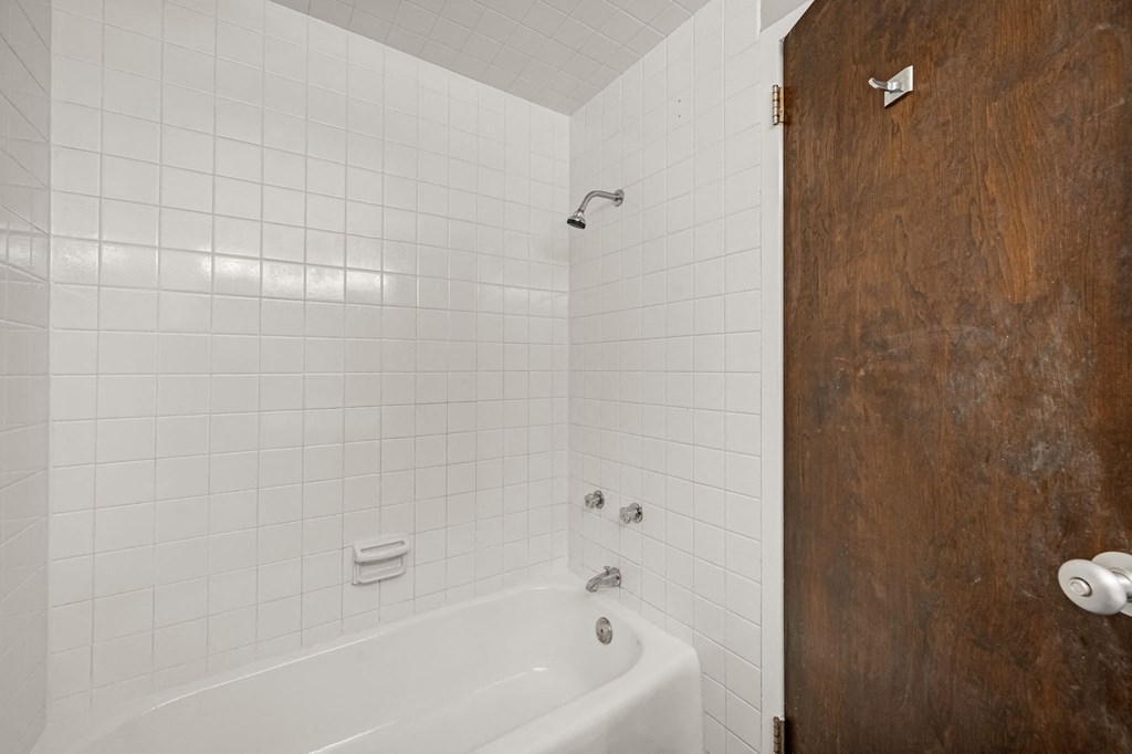 a white bathroom with a white tub and a wooden door
