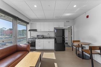A kitchen with white cabinets and a black refrigerator.