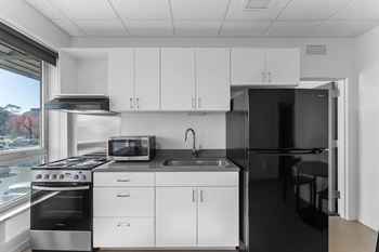 A modern kitchen with white cabinets and black countertops.
