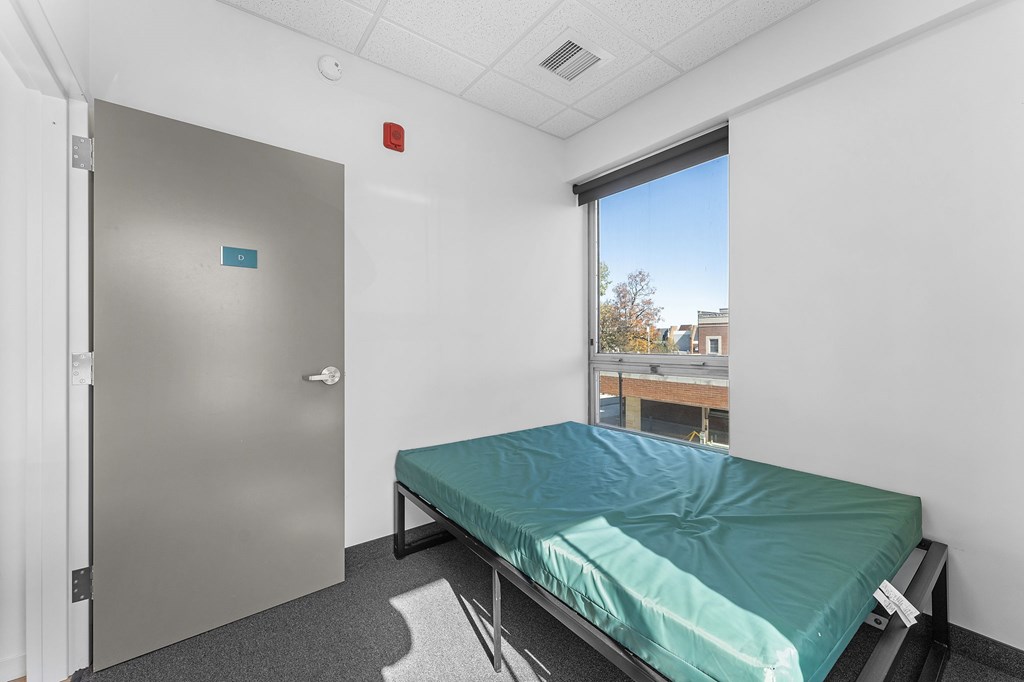 A bedroom with a bed, a door, and a window.