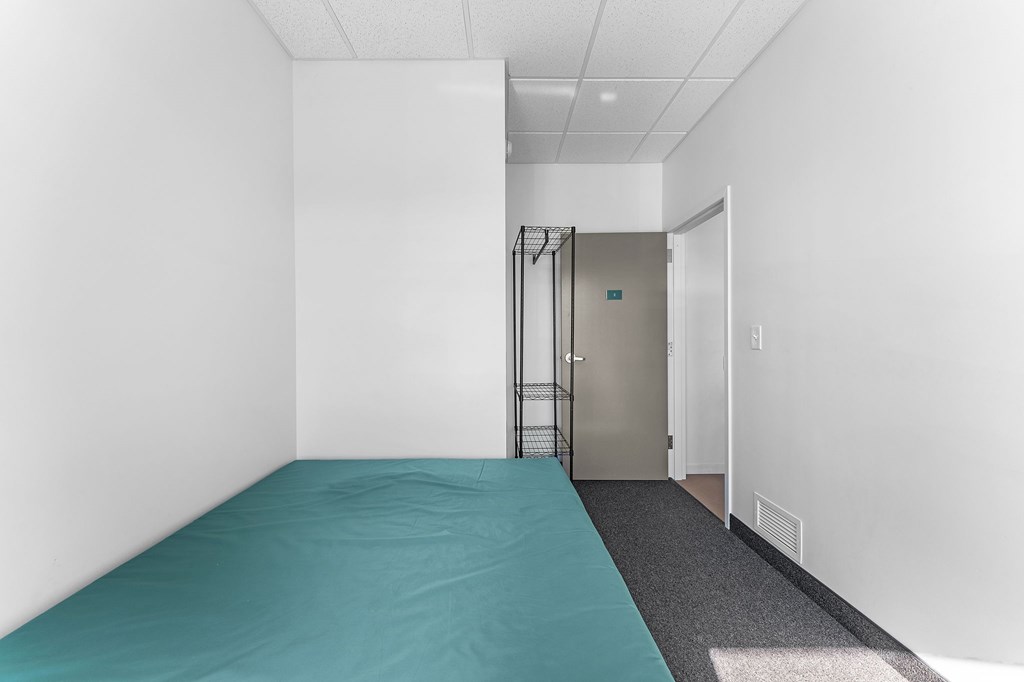 A room with a blue mattress and a metal gate.