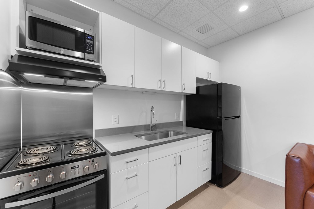 A modern kitchen with a stove, microwave, and refrigerator.