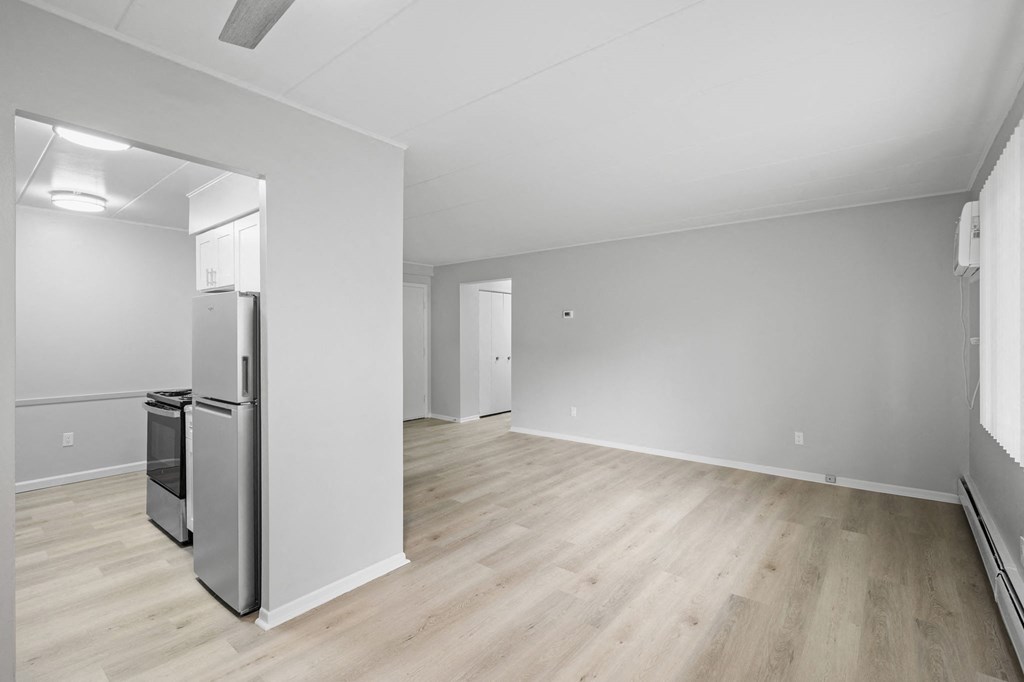 an empty living room with a refrigerator in it