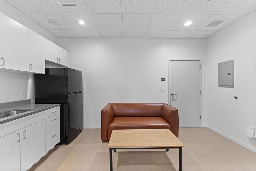 A kitchen with a black refrigerator and white cabinets.