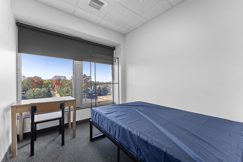 A bedroom with a bed, desk, and chair.